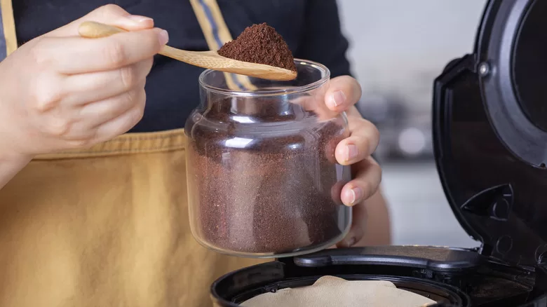 Hands measuring coffee from jar