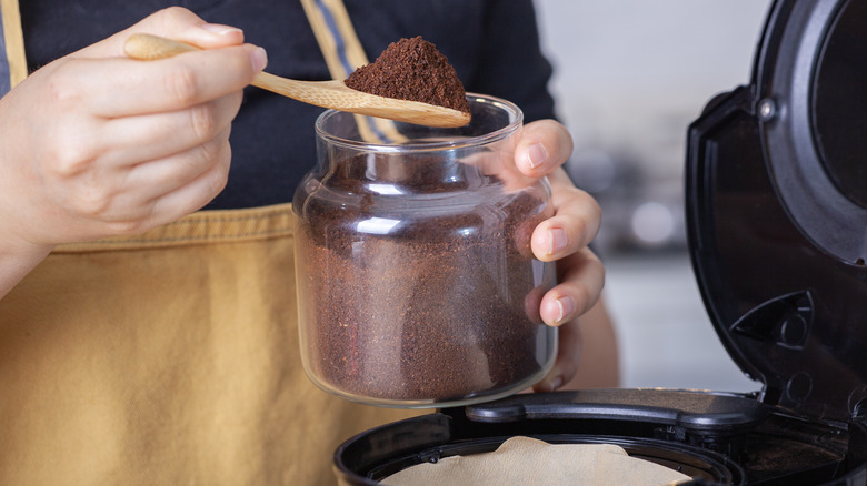 Hands measuring coffee from jar