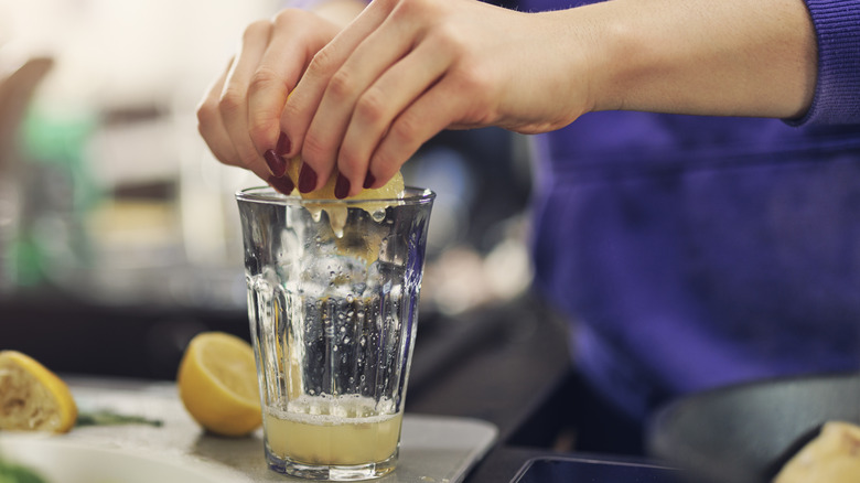 Lady squeezing lemon juice into a cup