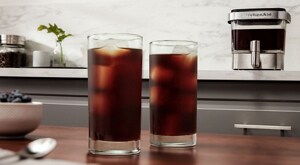 Two tall glasses of iced cold brew coffee on counter